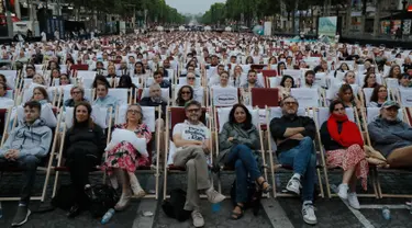 Orang-orang menonton film gratis yang diputar di ruang terbuka di jalan Champs Elysees, Paris (7/7/2019). Pemutaran bioskop luar ruangan gratis di Paris musim panas ini menayangkan film Prancis dengan teks bahasa Inggris, untuk membantu Anglophones mengikuti budaya Prancis. (AP Photo/Michel Euler)