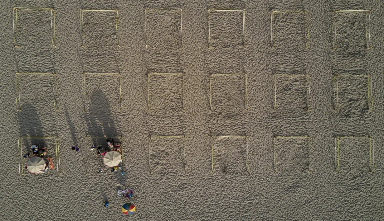 Para pengunjung berjemur dalam pembatas untuk menghindari keramaian di tengah pandemi COVID-19 di Pantai Lima, Peru, Rabu (21/12/2021). Di pantai-pantai populer di Lima, pihak berwenang memutuskan membuat pembatas untuk mencegah kerumunan pengunjung. (Ernesto BENAVIDES/AFP)