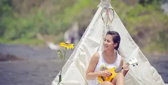 Ada-ada saja gaya Pevita Pearce saat bersantai di pantai. Lihat di belakangnya ada tenda fantasi. Sambil memainkan ukulele ia berdendang. (instagram @pevpearce)