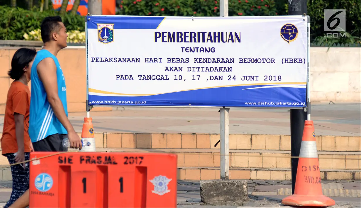 Warga melintas di depan spanduk pemberitahuan peniadaan pelaksanaan Hari Bebas Kendaraan Bermotor (HBKB) di Bundaran Hotel Indonesia, Jakarta, Minggu (3/6). Pelaksanaan HBKB akan ditiadakan pada 10, 17, dan 24 Juni 2018. (Liputan6.com/Helmi Fithriansyah)