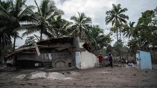 <span>Penduduk desa menyelamatkan apa yang mereka dapat dari rumah mereka yang rusak akibat erupsi Gunung Semeru di Desa Sumber Wuluh, Lumajang, Jawa Timur, Senin (6/12/2021). Desa Sumber Wuluh luluh lantak mengakibatkan puluhan rumah rusak dan ratusan warga mengungsi. (Juni Kriswanto/AFP)</span>