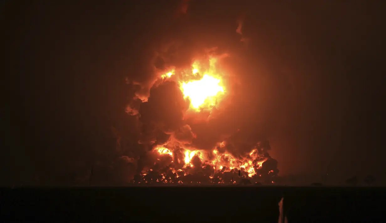 Langit malam bersinar dari api yang menghanguskan Kilang Pertamina Balongan di Indramayu, Jawa Barat, Senin (29/3/2021). Ratusan orang dievakuasi dari desa terdekat setelah kebakaran besar terjadi di kilang tersebut. (AP Photo)