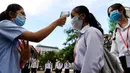 Siswa yang mengenakan masker diukur suhu tubuhnya setibanya di kompleks sekolah mereka ketika sekolah dibuka kembali di Phnom Penh, Senin (7/9/2020). Sekolah-sekolah di Kamboja dibuka kembali pada Senin (7/9) setelah enam bulan ditutup akibat COVID-19. (TANG CHHIN Sothy /AFP)