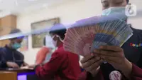 Petugas menunjukkan mata uang rupiah di penukaran uang di Jakarta, Senin (9/11/2020). Rupiah dibuka di angka 14.172 per dolar AS, menguat jika dibandingkan dengan penutupan perdagangan sebelumnya yang ada di angka 14.210 per dolar AS. (Liputan6.com/Angga Yuniar)