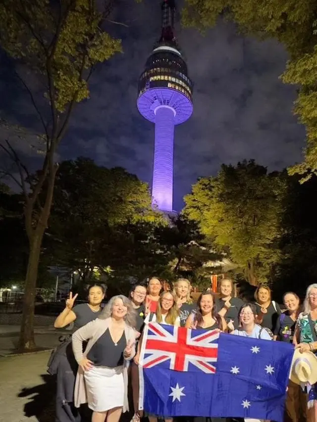 Fans BTS asal Australia berfoto depan Namsan Tower yang disinari cahaya ungu. (Foto: Instagram bts_australia)
