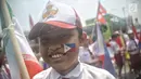 Seorang siswa SD mengenakan atribut bendera negara peserta Asian Games 2018 saat menyambut Kirab Obor di kawasan Jati Padang, Pasar Minggu, Rabu (15/8). Mereka memenuhi jalanan untuk menyaksikan langsung Pawai Obor Asian Games (Liputan6.com/Faizal Fanani)
