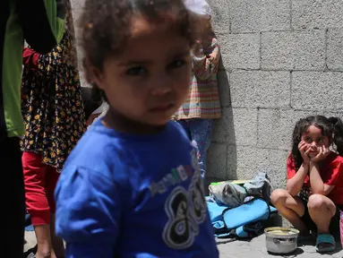Anak-anak Palestina menunggu di dekat dapur umum yang membagikan makanan siap saji di kamp pengungsi Nuseirat di Jalur Gaza tengah pada 5 Mei 2025. (Eyad BABA/AFP)
