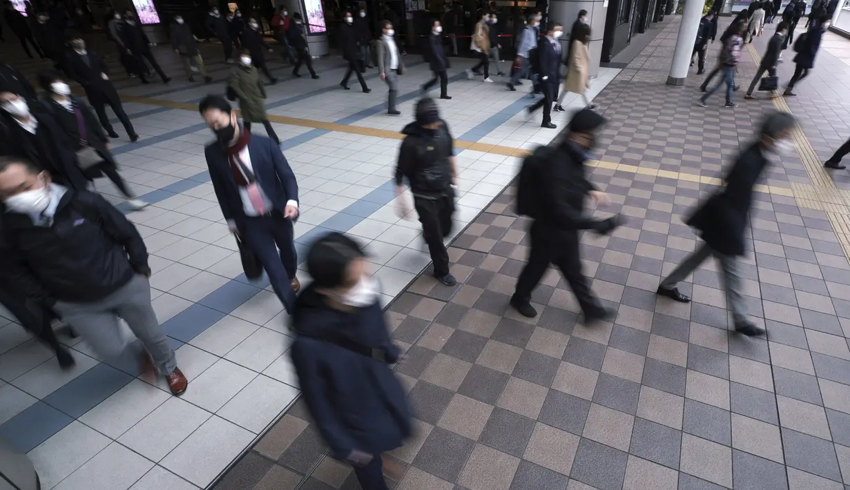 Penumpang kereta mengenakan masker wajah berjalan selama jam sibuk di Stasiun Shinagawa di Tokyo, Senin (22/3/2021). Perdana Menteri Jepang Yoshihide Suga pada Senin mencabut keadaan darurat virus corona di Tokyo dan tiga prefektur lainnya yang tersisa. (AP Photo/Eugene Hoshiko)