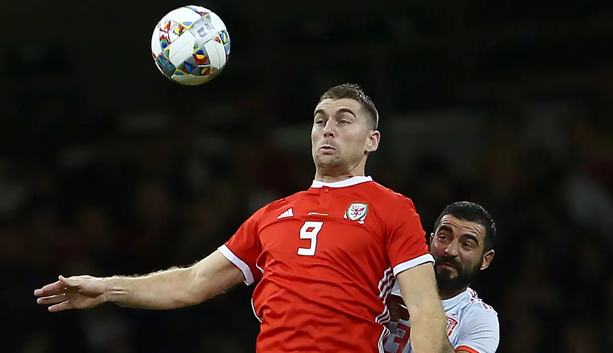 Striker Wales, Sam Vokes berusaha mengontrol bola dari kawalan bek Spanyol, Raul Albiol saat bertanding pada uji coba internasional di Stadion Principality, Cardiff, Inggris (11/10). Spanyol menang telak 4-1 atas Wales. (AFP Photo/Geoff Caddick)
