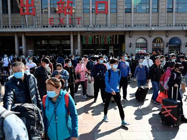 Orang-orang tiba di stasiun kereta api Beijing pada hari terakhir libur nasional "golden week", Kamis (7/10/2021). Liburan yang kerap disebut sebagai The Golden Week Holiday ini adalah peringatan berdirinya Republik Rakyat China pada tahun 1949. (JADE GAO / AFP)