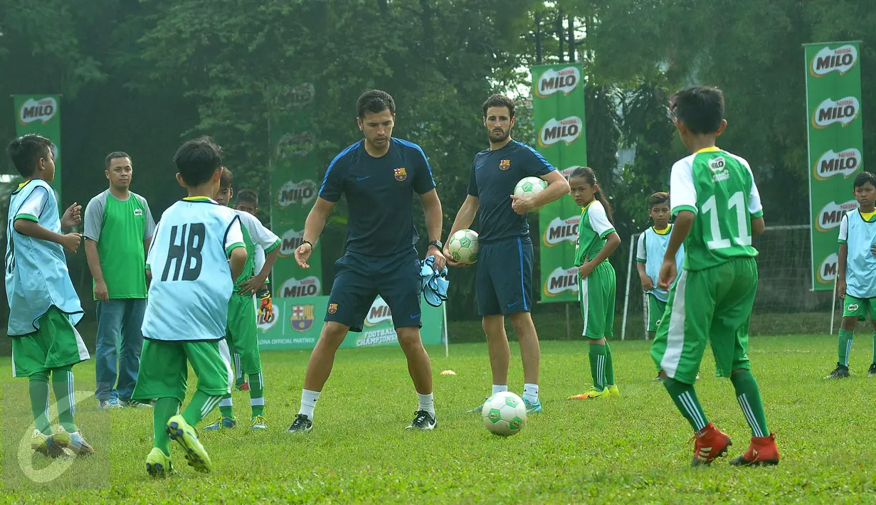Tim pelatih dari FC Barcelona, Jordi Fernandes (kanan) dan Marti Vila saat memberikan pelatihan sepak bola kepada anak-anak hasil seleksi Milo Football Championship 2017, Tangerang Selatan, Jumat (21/4). (Liputan6.com/Helmi Afandi)