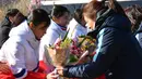 Tim Korea Selatan (kanan) memberi bunga kepada tim hoki es Korea Utara saat tiba di pusat pelatihan nasional Jincheon, Korsel (25/1). (AFP Photo/Pool/ Kyung-Seok)