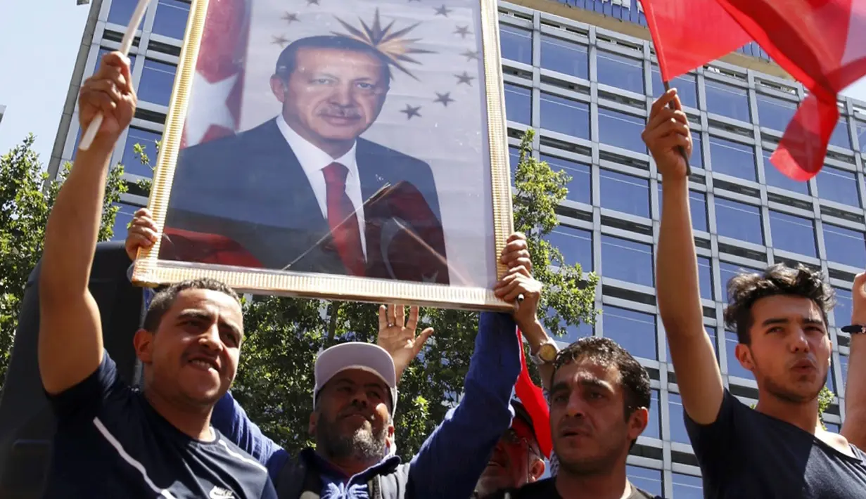 Warga membawa foto Presiden Turki, Tayyip Erdogan sambil mengibarkan bendera nasional mereka di Ankara,  Sabtu (16/7). Ratusan warga turun ke jalan untuk merayakan kegagalan kudeta militer di Turki. (REUTERS/ Tumay Berkin)