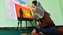 Foto yang diambil pada 5 Desember 2019 menunjukkan seniman Robaba Mohammadi melukis menggunakan mulut di studionya di Kabul. Gadis 19 tahun itu dilahirkan  dengan kelumpuhan parsial anggota tubuhnya sehingga tidak mampu mengendalikan tangan dan kakinya. (NOORULLAH SHIRZADA/AFP)