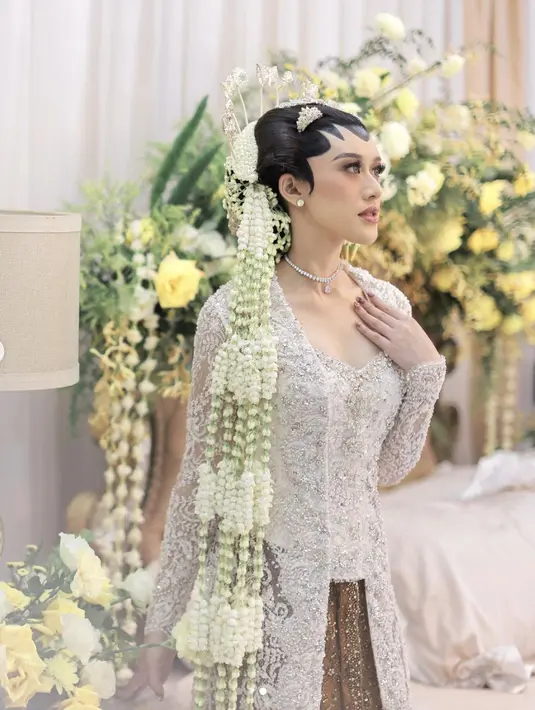 Kebaya penganting putih semakin terlihat mewah dengan paduan payet silver. Aksen bukaan dada yang memperindah tampilan juga menjadi keunikan tersendiri pada detail kebayanya. [Foto: Instagram/ Kusumaputeri]