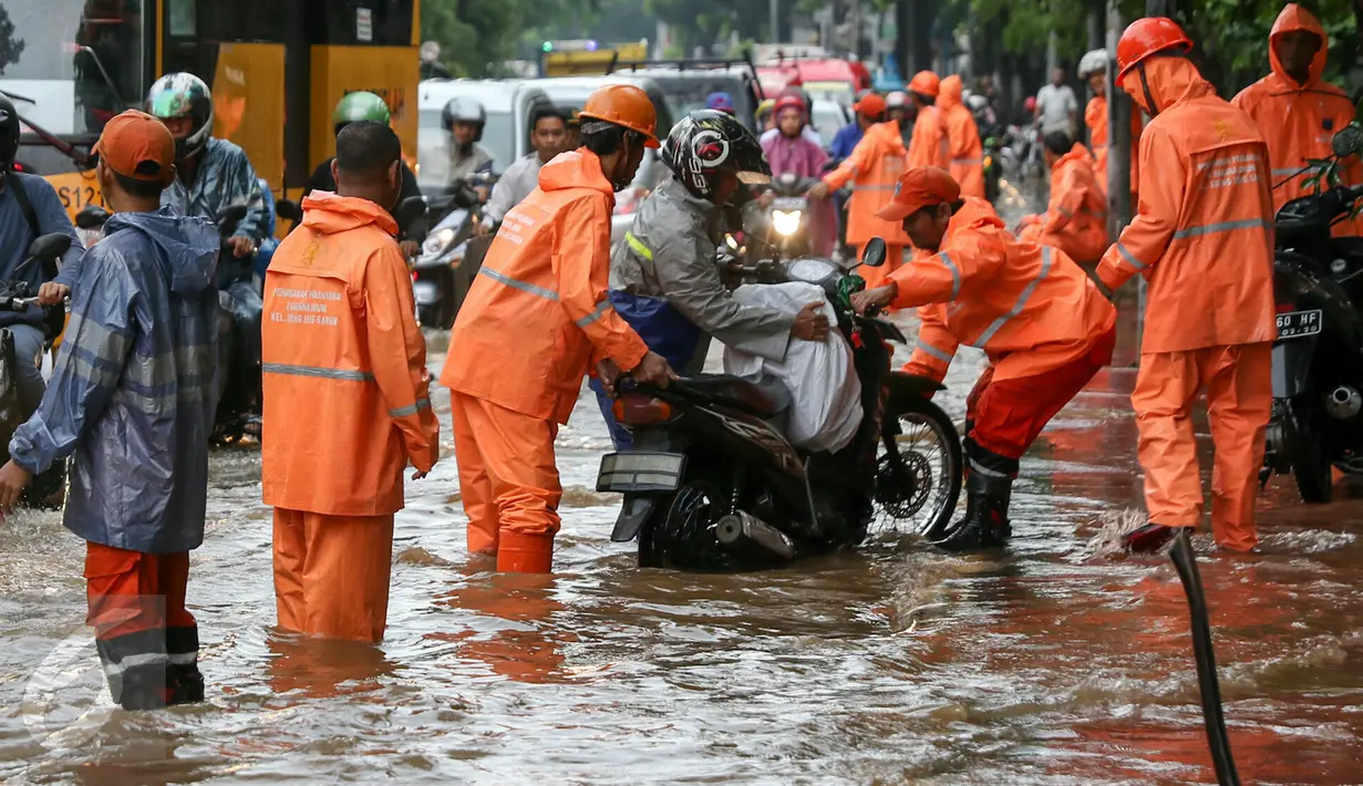 Petugas PPSU membantu pengedara motor yang mogok di jalan Lenteng Agung, Jakarta, Jumat (12/2). Banjir di jalan Lenteng Agung ketinggian airnya hingga 30-50cm. (Liputan6.com/Yoppy Renato)