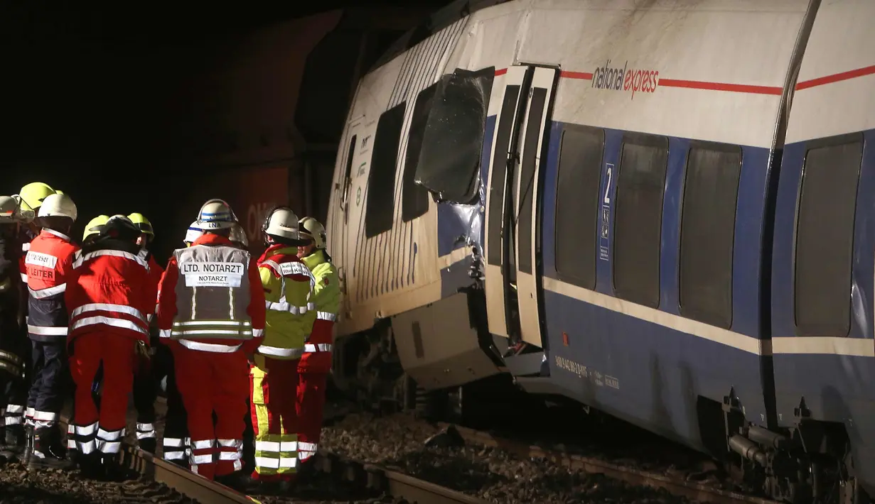 Petugas pemadam kebakaran berdiri di samping gerbong yang rusak usai terjadinya tabrakan dengan kereta lainnya di Meerbusch, Jerman, (5/12). Puluhan penumpang alami luka-luka dan tidak ada korban jiwa. (Arnulf Stoffel / dpa via AP)