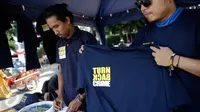 Penjual saat menjual baran dagangannya yang bertulisan "Turn Back Crime" saat Car Free Day kawasan Bunderan HI, Jakarta (13/3). Penggunaan merk 'Turn Back Crime' bertujuan untuk kampanye waspada tindak kejahatan. (Liputan6.com/Faizal Fanani)