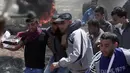 Para pengunjuk rasa Palestina membawa seorang pria yang terluka selama protes di perbatasan Jalur Gaza dengan Israel, (6/4). (AP Photo/Khalil Hamra)