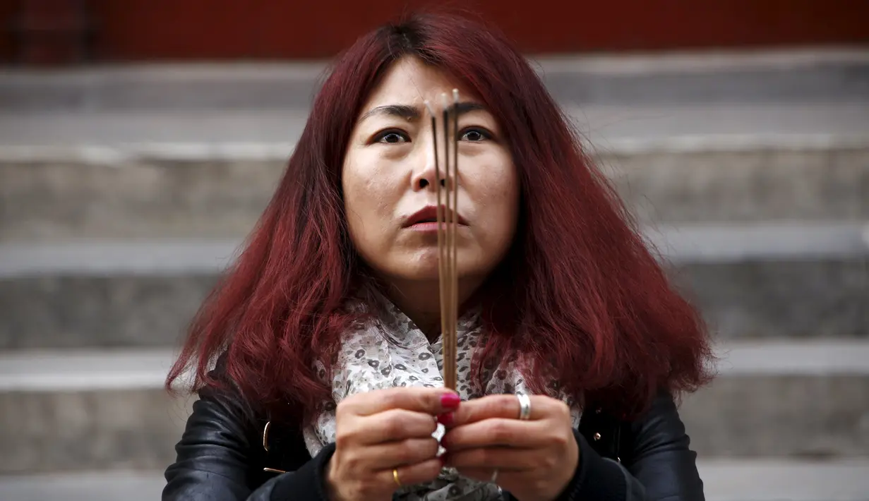 Zheng Liping istri salah satu penumpang pesawat MH370 berdoa untuk suaminya, Ju Kun yang hilang pada tahun 2014 di Kuil Lama di Beijing, Cina,(8/3). Pesawat jet berisi 239 penumpang dan awak ini hilang sejak 8 Maret 2014. (REUTERS/Kim Kyung-hoon)