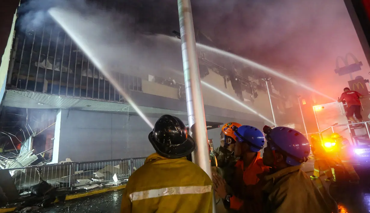 Petugas pemadam kebakaran berusaha memadamkan api saat terjadi kebakaran di pusat perbelanjaan atau mal di kota Davao, Filipina Selatan (23/12). (AFP Photo / Manman Dejeto)