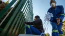 Silva Cossa dan Leonard Makuya, dua orang pengurus, mengikat pita ke pagar gereja St James Presbyterian di Bedford Gardens, Johannesburg, Rabu (29/7/2020). Pita tersebut mewakili warga Afrika Selatan yang meninggal akibat virus corona COVID-19. (AP Photo/Themba Hadebe)