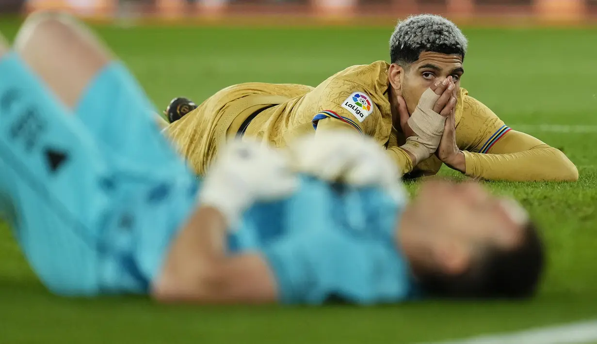 Reaksi pemain Barcelona, Ronald Araujo pada laga lanjutan Liga Spanyol 2022/2023 melawan Almeria yang berlangsung di Power House Stadium, Senin (27/02/2023) dini hari WIB. (AP Photo/Jose Breton)