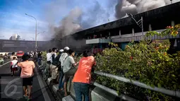Sejumlah warga menonton petugas pemadam kebakaran yang tengah berusaha memadamkan api yang melahap pusat perbelanjaan Blok III Pasar Senen, Jakarta Pusat, Kamis (19/1). (Liputan6.com/Faizal Fanani)