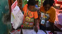 Warga melihat surat suara saat ia bersiap untuk memberikan suaranya dalam pemilihan presiden dan legislatif di sebuah TPS di distrik Kwamki Narama, Kabupaten Mimika, Papua Tengah pada tanggal 14 Februari 2024. (ADEK BERRY/AFP)
