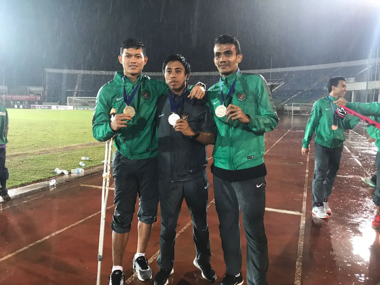 Kiper Timnas Indonesia U-19, Muhammad Riyandi, foto dengan medali perunggu di tengah guyuran hujan di Stadion Thuwunna, Yangon, Minggu (17/9/2017). (Bola.com/Aning Jati)