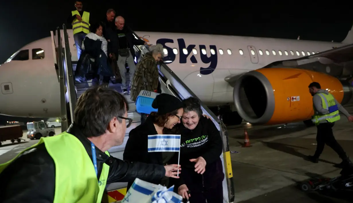 Pengungsi Yahudi Ukraina dan imigran baru yang melarikan diri dari perang di negara mereka turun dari pesawat setibanya di Bandara Ben Gurion, Tel Aviv, Israel, 22 Desember 2022. Sebanyak 100 orang Yahudi Ukraina tiba di Israel, termasuk beberapa penumpang yang terbaring di tempat tidur dan dalam kondisi sakit. (GIL COHEN-MAGEN/AFP)