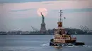 <p>Bulan purnama terlihat di belakang Patung Liberty, New York City, Amerika Serikat, Kamis (7/5/2020). Fenomena supermoon atau di belahan Bumi lain disebut flower moon ini merupakan yang terakhir di tahun 2020. (Johannes EISELE/AFP)</p>