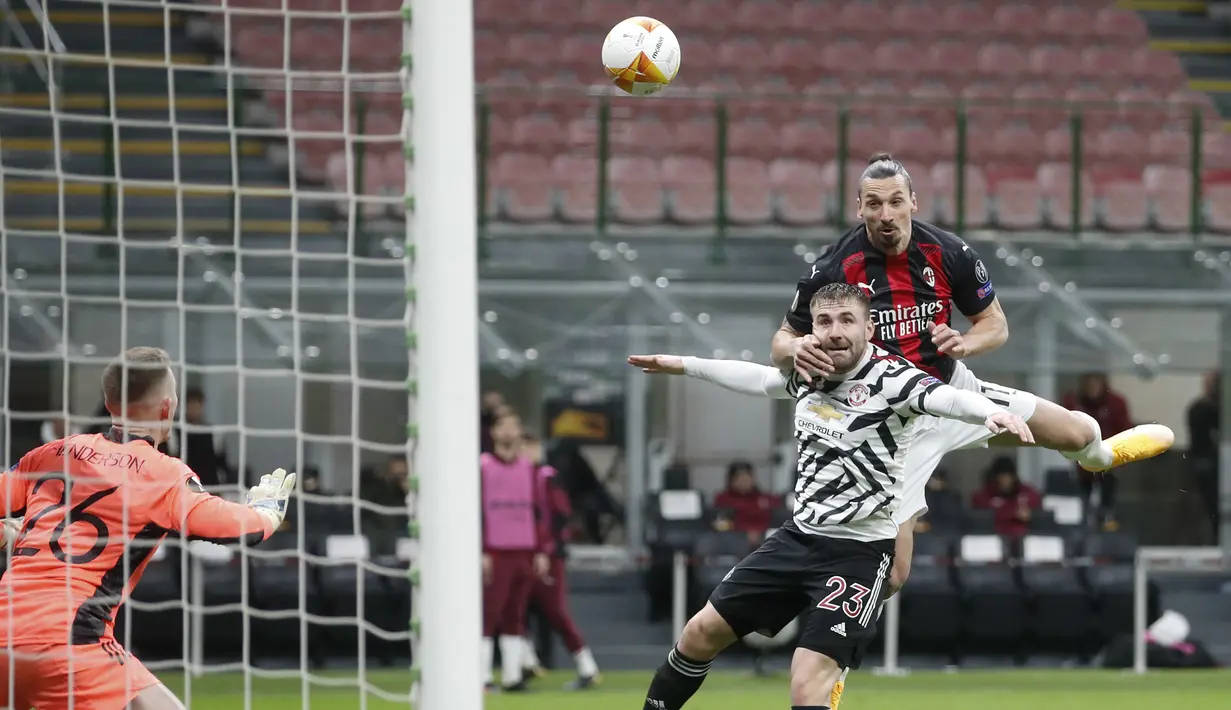 Striker AC Milan, Zlatan Ibrahimovic melompat untuk menyundul bola di atas bek Manchester United, Luke Shaw dalam laga leg kedua babak 16 besar Liga Europa 2020/2021 di San Siro Stadium, Milan, Kamis (18/3/2021). AC Milan kalah 0-1 dari Manchester United. (AP/Antonio Calanni)