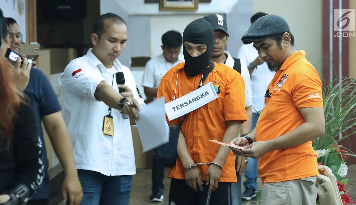 Tersangka HS pelaku kasus pembunuhan satu keluarga di Bekasi (tengah) melakukan pra-rekonstruksi di Polda Metro Jaya, Jakarta, Senin (19/11). 35 adegan diperagakan dari 57 yang akan diperagakan saat rekonstruksi. (Liputan6.com/Helmi Fithriansyah)
