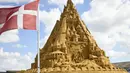 Patung pasir tertinggi di dunia yang sedang dibangun terlihat di latar belakang, di Blokhus, Denmark, Rabu (7//2021). Perancangnya, Wilfred Stijger mengatakan pandemi corona covid-19 telah menjadi inspirasi pembuatan istana pasir tersebut.  (Claus Bjoern Larsen/Ritzau Scanpix/AFP)