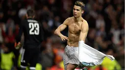 Striker Real Madrid Cristiano Ronaldo melepas jerseynya saat merayakan gol usai membobol gawang Juventus lewat tendangan penalti dalam petandingan Liga Champions di stadion Santiago Bernabeu, Madrid (11/4). (AFP Photo/Oscar Del Pozo)