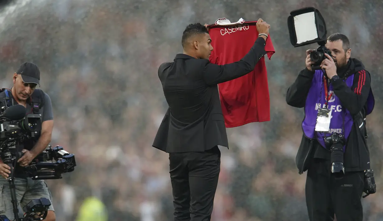 Pemain baru Manchester United Casemiro memegang jerseynya ketika memberi semangat kepada para pendukung sebelum sesaat sebelum laga MU vs Liverpool dimulai di stadion Old Trafford, Senin (22/8/2022). Gelandang asal Brasil itu telah menuntaskan transfernya dan menandatangani kontrak sampai 2026. (AP Photo/Dave Thompson)
