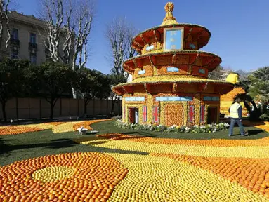 Seorang pria berjalan di dekat patung yang terbuat dari jeruk dan lemon menjelang festival Lemon di Menton, sebuah kota kecil di Perancis, Rabu (12/2/2015). (AFP PHOTO/Valery Hache)