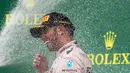 Pembalap Mercedes, Lewis Hamilton disemprot sampanye usai memenangkan GP F1 Amerika Serikat di Sirkuit The Americas, Minggu (25/10). Ini merupakan gelar juara dunia ketiga bagi Hamilton setelah sebelumnya diraih pada 2008 dan 2014. (REUTERS/Adrees Latif)