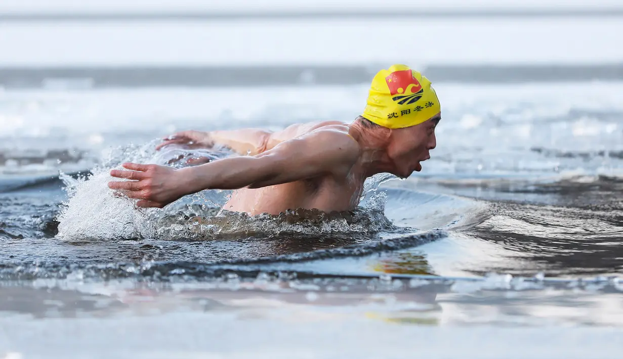 Seorang pria berenang di danau yang sebagaian beku dengan es saat suhu minus 20 derajat Celcius di Shenyang di provinsi Liaoning timur laut China (10/12). (AFP Photo/Str/China Out)