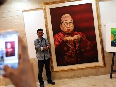 Pengunjung berfoto di dekat lukisan Presiden RI ke-4 Abdurrahman Wahid (Gusdur) saat pameran di Gedung PBNU, Jakarta, Senin (30/1). Pameran tersebut digelar dalam rangka Harlah NU ke-91. (Liputan6.com/Johan Tallo)