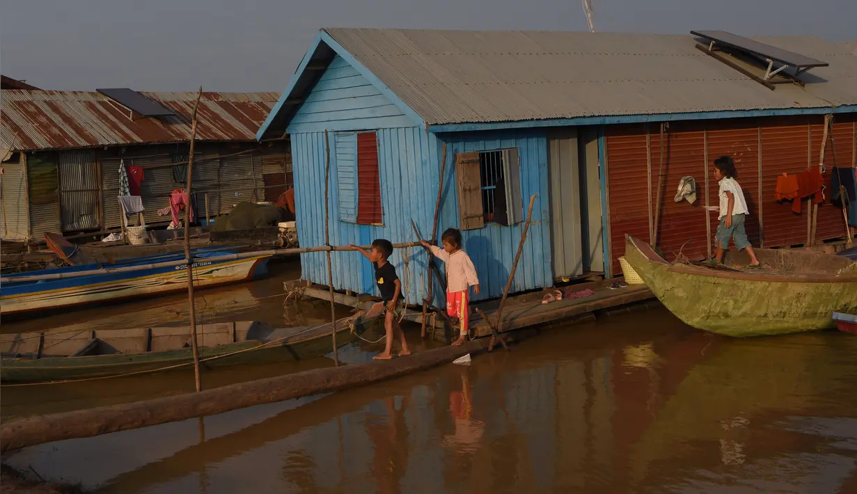 Anak-anak berjalan di atas papan kayu di sebuah desa terapung di sepanjang sungai Siem Reap di Siem Reap, Kamboja (5/12/2019). Sungai Siem Reap adalah sungai yang mengalir melalui Provinsi Siem Reap, di barat laut Kamboja. (AFP/Manan Vatsyayana)