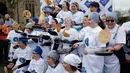 Para peserta berpose setelah mengikuti lomba lari sembari membawa wajan berisi pancake di kota Olney, Inggris, Selasa (13/2). Tidak hanya membawa wajan, peserta juga harus membolak-balikan pancake samcil tetap berlari. (AP Photo/Matt Dunham)