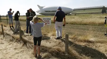 Sejumlah orang mengambil gambar dari pesawat Airlander 10 setelah gagal mendarat di Cardington Airfield, Inggris, Rabu (24/8). Pesawat yang diklaim terbesar di dunia itu rusak karena harus menukik tajam ketika melakukan pendaratan (REUTERS/Darren Staples)