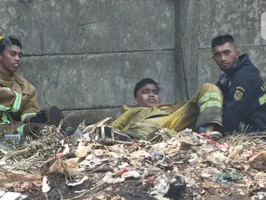 Petugas pemadam kebakaran beristirahat usai memadamkan api di lapak ban bekas, Desa Bojong Nangka, Gunung Putri, Bogor, Kamis (22/4/2021). Banyaknya bahan yang mudah terbakar dan sumber api yang berasal dari bawah tumpukan ban membuat  api di lokasi belum juga padam. (Liputan6.com/Herman Zakharia)