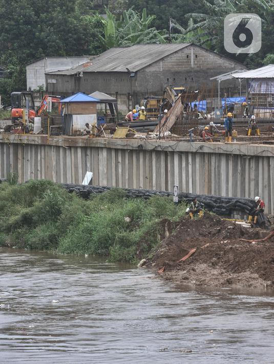 Aktivitas pekerja saat menyelesaikan proyek pembangunan saringan sampah Kali Ciliwung segmen Jalan TB Simatupang, Jakarta, Minggu (12/2/2023). Proyek Saringan Sampah senilai Rp 195 miliar ini awalnya ditargetkan rampung pada Januari 2023. Karena terhambat pembebasan lahan, Pemprov DKI akhirnya mengundur waktu pengerjaan hingga Maret mendatang. (merdeka.com/Iqbal S Nugroho)