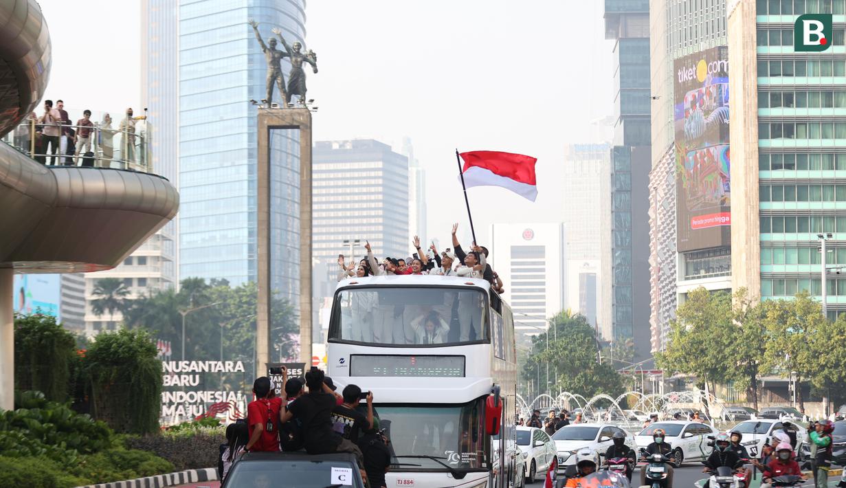 Sejumlah atlet dan ofisial Kontingen Indonesia pada Olimpiade Paris 2024, termasuk peraih medali emas, Veddriq Leonardo dan Rizki Juniansyah serta peraih medali perunggu, Gregoria Mariska Tunjung mengikuti pawai dengan menaiki bus tingkat terbuka Transjakarta di Bundaran HI menuju Istana Negara, Jakarta Pusat, Kamis (15/8/2024). (Bola.com/Abdul Aziz)