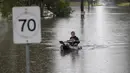 Seorang pria mengayuh melalui air banjir di Londonderry di pinggiran barat Sydney, Australia (22/3/2021).  Negara bagian New South Wales yang padat penduduknya telah mengeluarkan lebih banyak perintah evakuasi menyusul banjir terburuk dalam beberapa dekade. (AP Photo/Mark Baker)