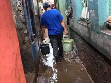 Warga membawa air untuk membersihkan lumpur sisa banjir yang menggenangi kawasan Rawajati, Jakarta Selatan, Selasa (6/2). Banjir yang mulai surut dimanfaatkan warga untuk membersihkan lumpur. (Liputan6.com/Immanuel Antonius)