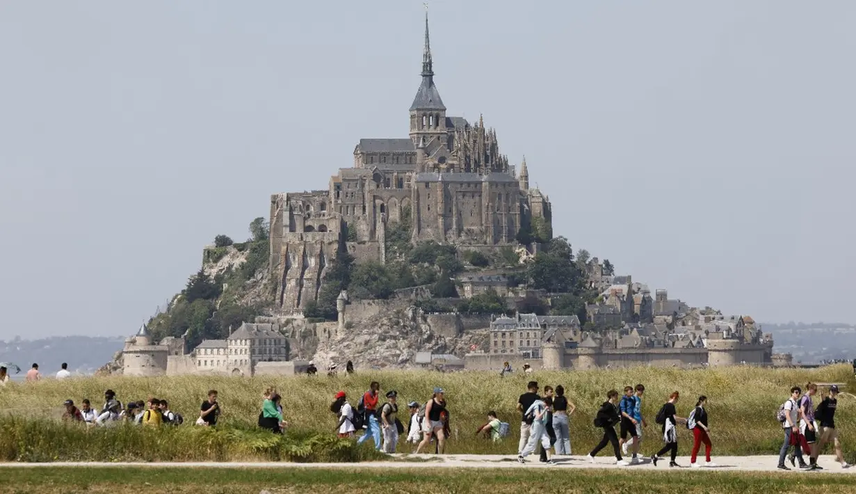 <p>Orang-orang berjalan melewati Biara Mont-Saint-Michel saat kunjungan Presiden Prancis Emmanuel Macron di Normandia, Le Mont-Saint-Michel, Prancis, Senin (5/6/2023). (Ludovic MARIN/POOL/ AFP)</p>